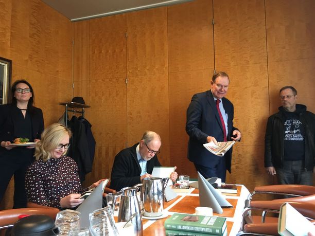 Paavo Lipponen saapui kirjanjulkistustilaisuuteen iltapäivälehdet kädessään. Rosila kirjoittaa pöydän päässä omistuskirjoitusta. Rosilan vieressä eduskunnan puhemiehenä 2015-2018 toiminut Maria Lohela.