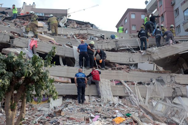 Pelastajat yrittävät päästä romahtaneisiin rakennuksiin jääneiden ihmisten luo Izmirissä. 