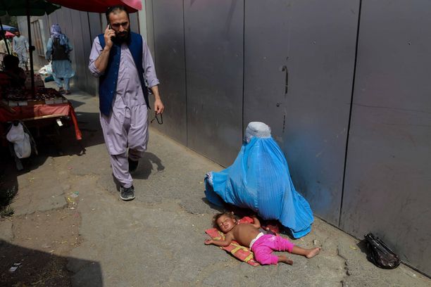 Nainen kerjää lapsensa kanssa Kabulin kadulla syyskuussa 2021.