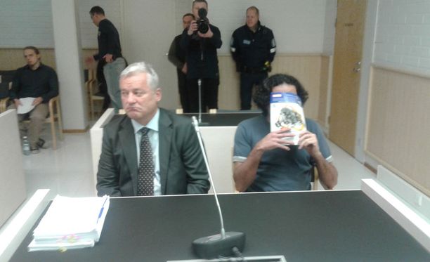 Sekä vanhempi syytetyistä (kuvassa) että nuorempi syytetyistä peitti kasvonsa oikeudessa tiistaina. Kuvassa myös vanhemman syytetyn asianajaja Mikael Knuuti. 