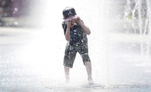 Pikkupoika vilvoittelee suihkulähteessä ennätyshelteiden piinaamassa Montrealissa.