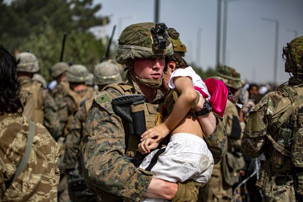 USA:n sotilas kantoi tyttöä Kabulin lentokentän portilla perjantaina. Kuvan on toimittanut USA:n merijalkaväki.