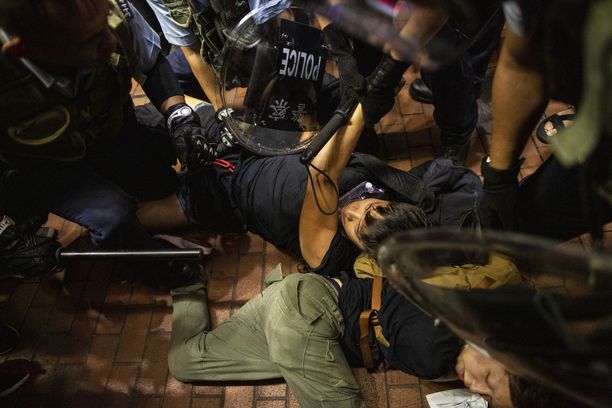 Mellakkapoliisit pitävät lakimuutosta vastustavaa mielenosoittajaa maassa Hongkongissa.