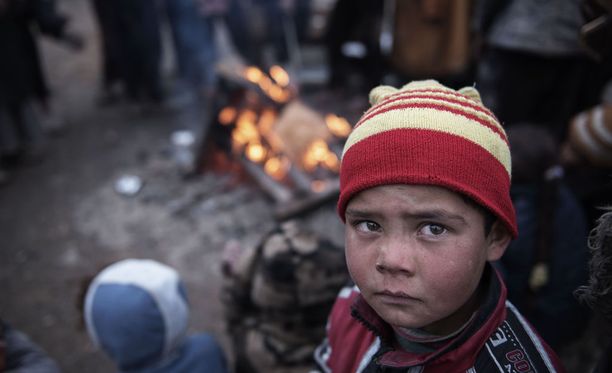 Lapsi lämmittelee nuotion edessä paettuaan Isisin ja Irakin joukkojen taistelua Mosulin lähellä maaliskuussa 2017.