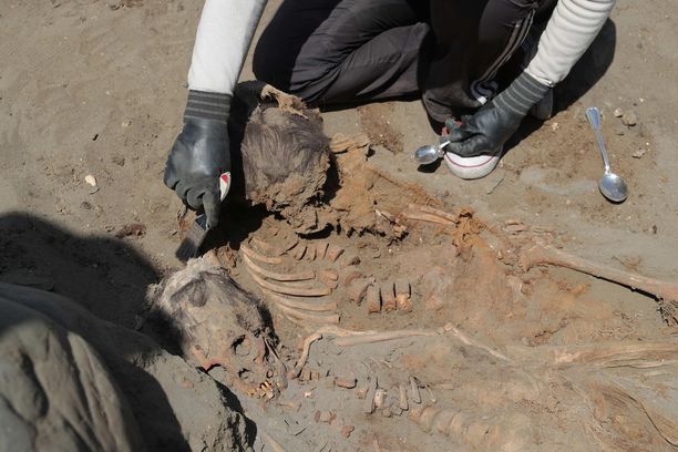 Arkeologit puhdistavat löydettyjen chimu-kulttuurissa uhrattujen lapsien luurankoja Perussa kesäkuussa 2018.