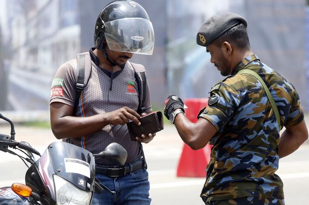 Srilankalainen viranomainen tarkisti moottoripyöräkuskin henkilöllisyyden Colombossa. Kuvituskuva.