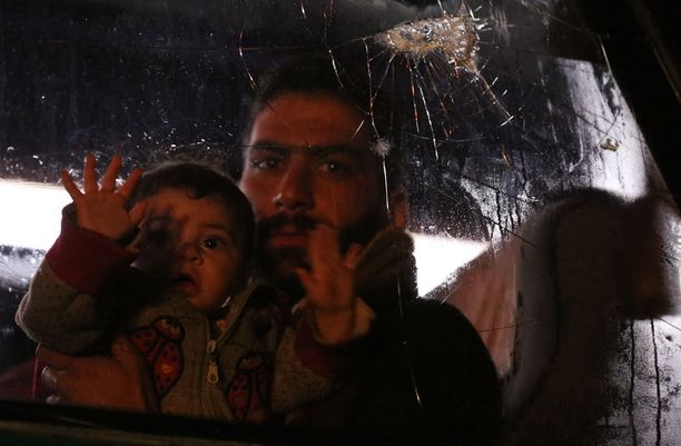 Doumasta Aleppoon paennut syyrialaismies lapsensa kanssa.
