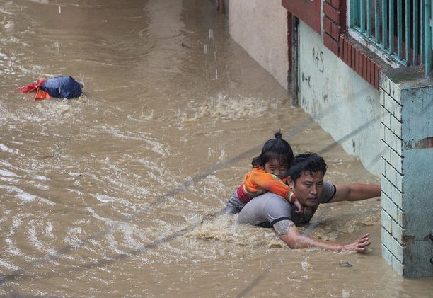 Mies kantaa selässään tytärtään tulvien valtaamassa Nepalin pääkaupungissa Kathmandussa 12. heinäkuuta.