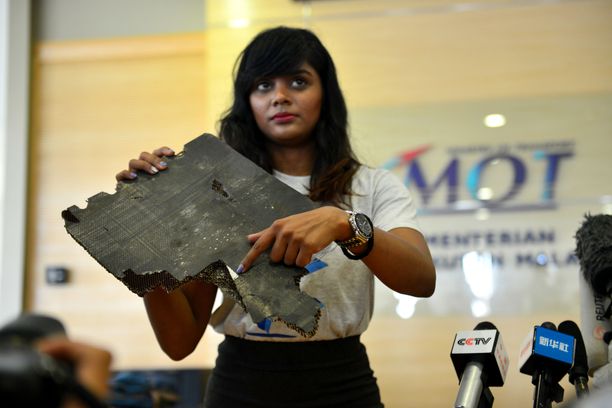 Yhden MH370:n matkustajan omainen pitelemässä palaa, jonka uskotaan kuuluneen turmakoneeseen.