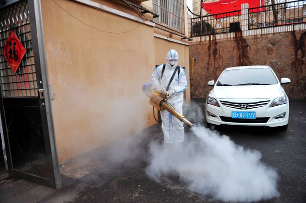 Vapaaehtoinen desinfioi asuinaluetta kiinalaisessa Qingdaon kaupungissa tiistaina. Kiinan hallinto on etsinyt ennalta ehkäiseviä keinoja, joiden avulla yritetään estää koronavirusta leviämästä.