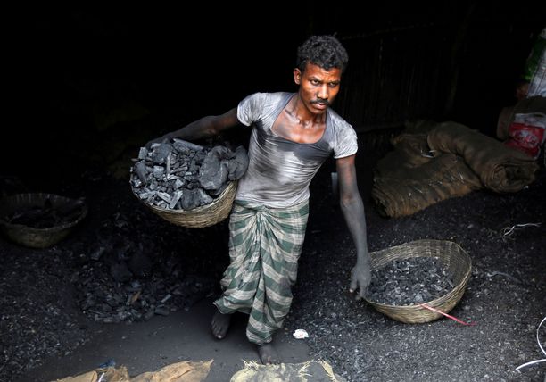 Työntekijä kantaa hiiltä korissa teollisuusalueella Intian Mumbaissa.