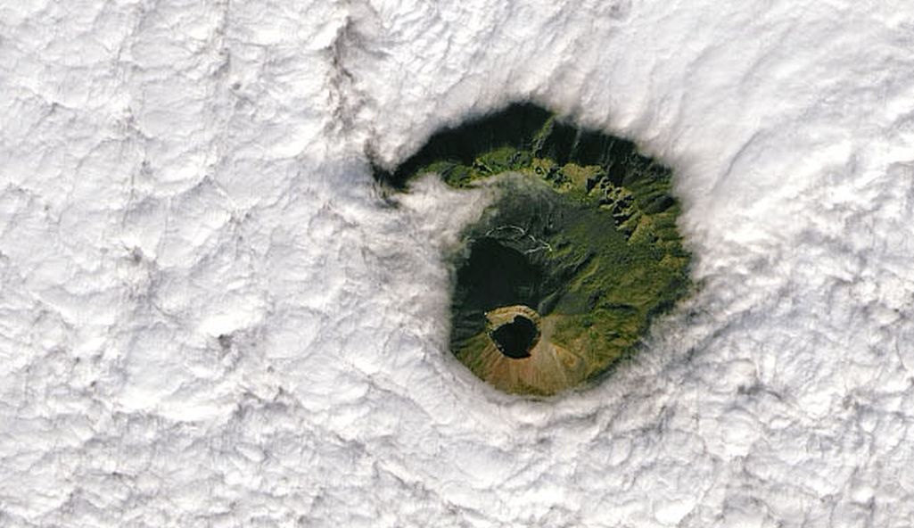 ”Maailman vaarallisin tulivuori” kurkistaa Nasan hienossa kuvassa pilvien raosta 