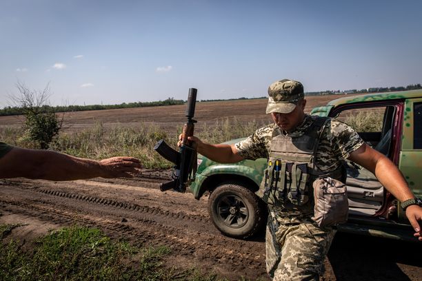 Ukrainalaissotilas ojentaa kiväärinsä tovereilleen lähellä rintamaa Mykolajivin alueella Etelä-Ukrainassa.