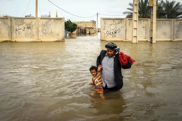 Iranilainen mies kantaa poikaansa tulvivassa kylässä lähellä Ahvazia.