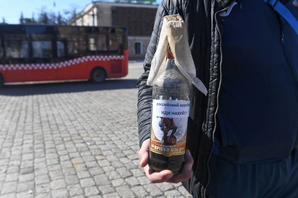 Ukrainalaismies pitelemässä Molotovin cocktailia Harkovassa Vapauden aukiolla. Pulloon on kirjattu terveiset, mihin venäläiset voivat painua.