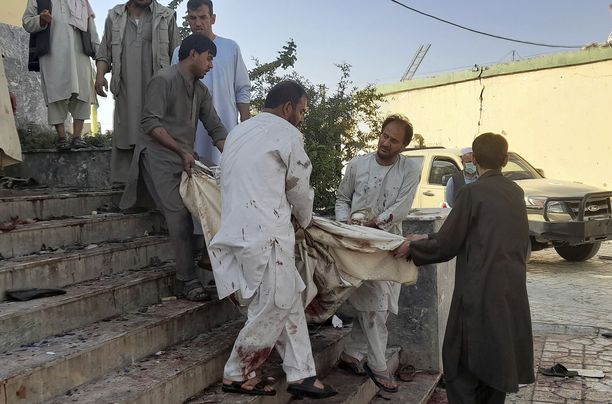 Ihmisiä kantamassa uhria ulos moskeijasta Afganistanin Kunduzissa.