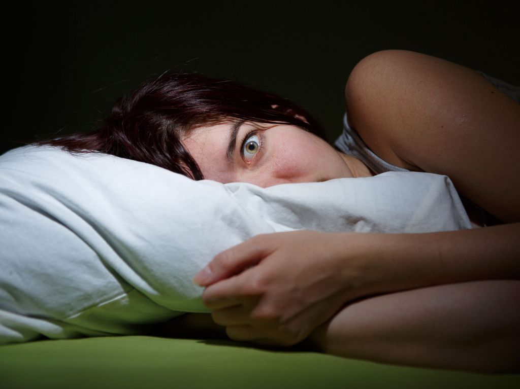 Young woman in bed  eyes opened suffering insomnia. Nightmare issues