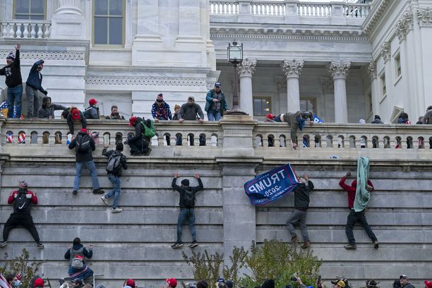 6. tammikuuta vuonna  2021 silloisen presidentin Donald Trumpin kannattajat mellakoivat Capitolissa. Kuvassa ihmiset kiipeävät alueella seinää ylös.
