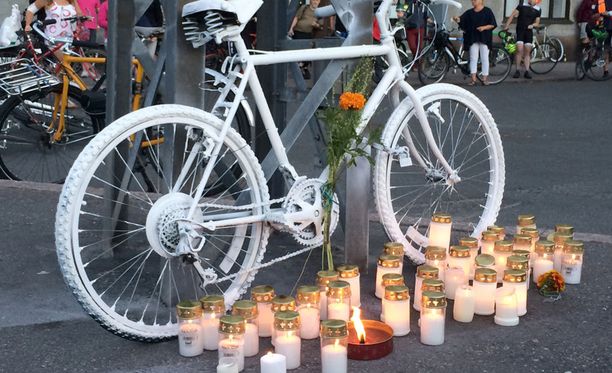 Ihmiset sytyttivät kynttilöitä onnettomuuspaikan viereen tuodun valkoisen polkupyörän luona.