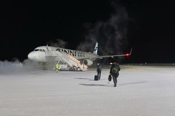 Ihmisiä menossa lentokoneeseen Ivalon lentokentällä joulukuussa. Kuvituskuva.