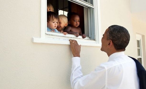 Obama tervehtii kuvassa lapsia. Tviitin lainaus on Nelson Mandelalta.